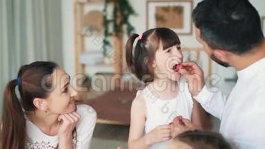 快乐的家庭在厨房，妈妈，爸爸和女儿吃草莓，慢动作
